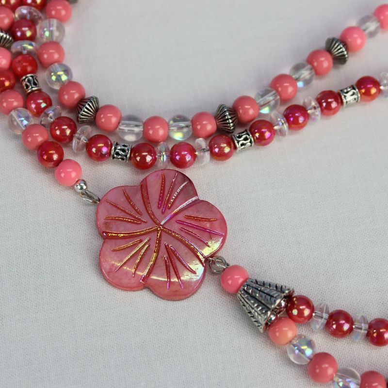Double strand asymmetrical necklace with shell flower focal, shell and glass beads in shades of pink, coral, and clear, silver plated beads, toggle clasp